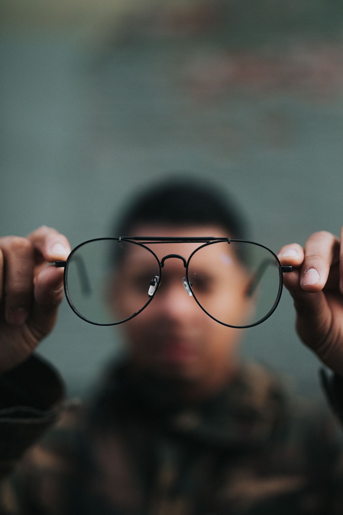 Image of a man holding glasses out from his face, but you can still see through them to his face, by Nathan Dumlao courtesy of Unsplash